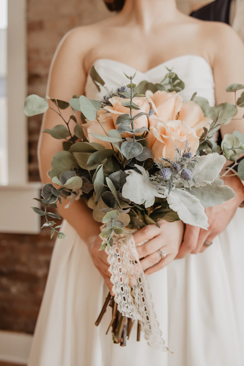 Bouquet de roses pêche et d’eucalyptus tenu par la mariée