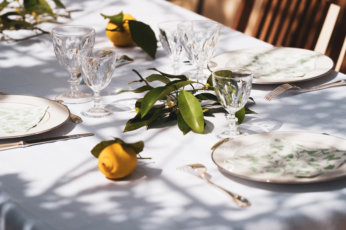 Table dressée au soleil avec verres en cristal, citrons et feuillages