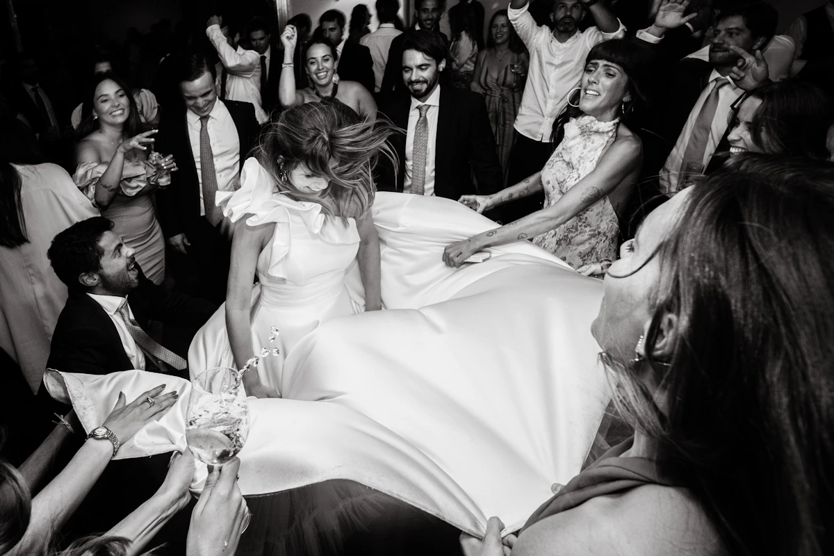 Mariée soulevée par les invités pendant la fête, en noir et blanc