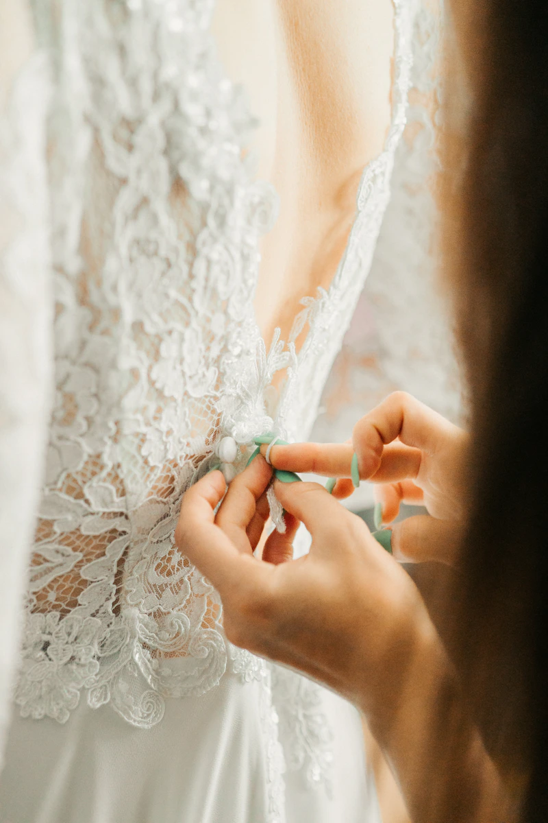 Mains qui ajustent les boutons dans le dos d’une robe en dentelle
