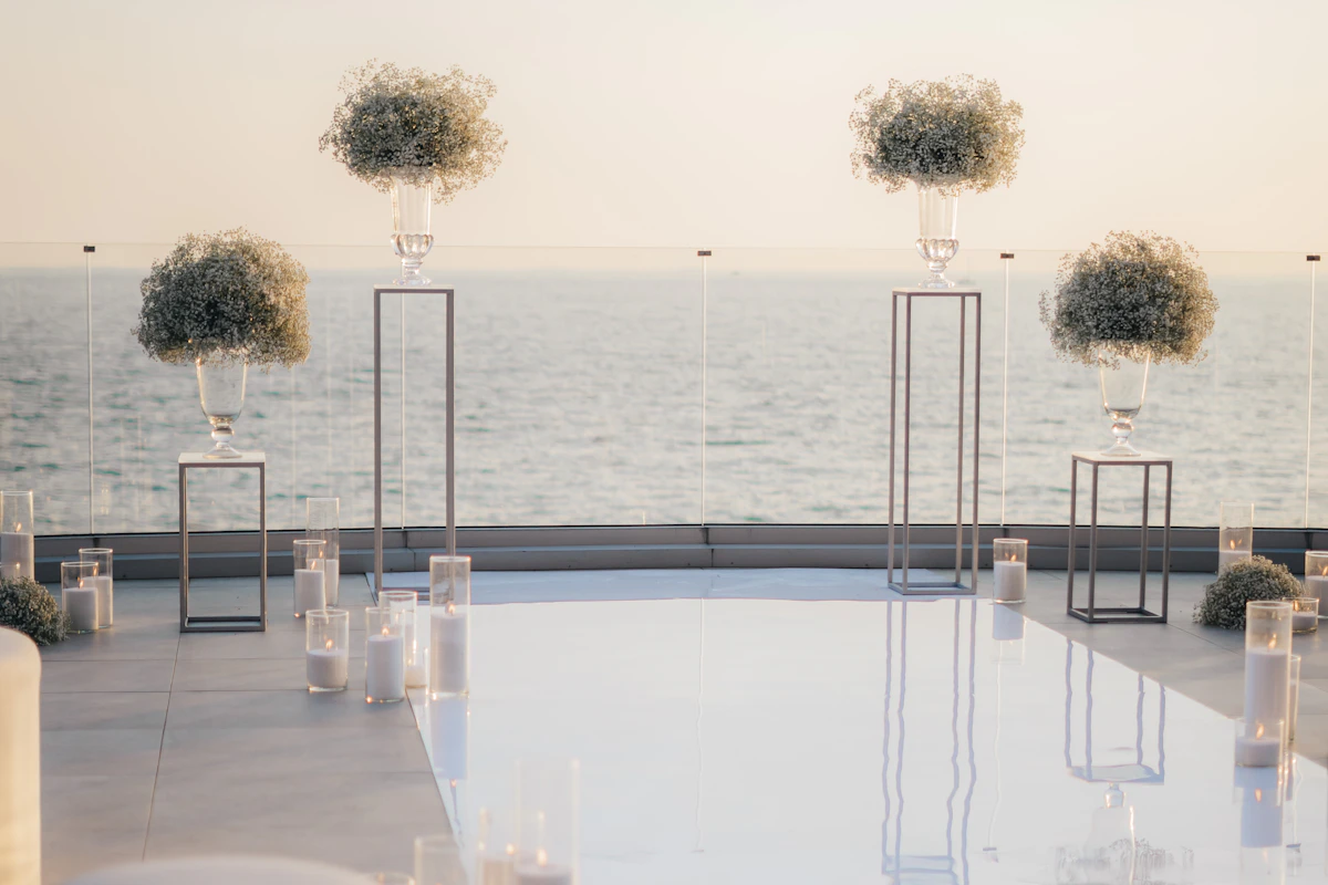 Allée de cérémonie en miroir sur une terrasse face à la mer, bordée de bougies